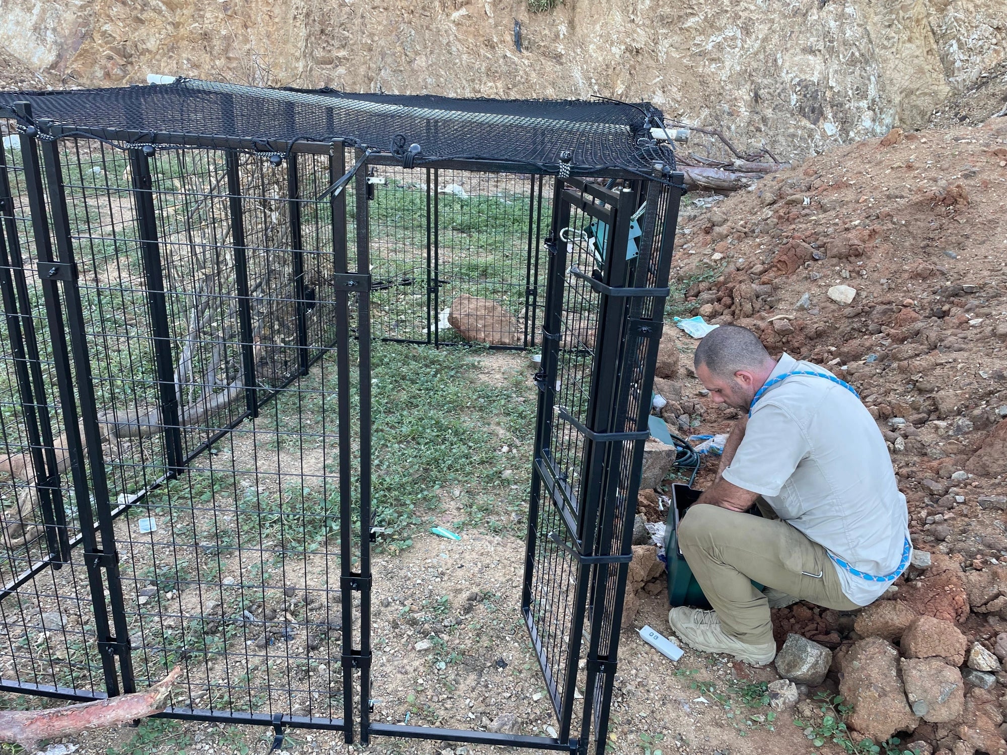 An organized collection of animal control equipment such as carriers, poles and gloves in a tiled room.