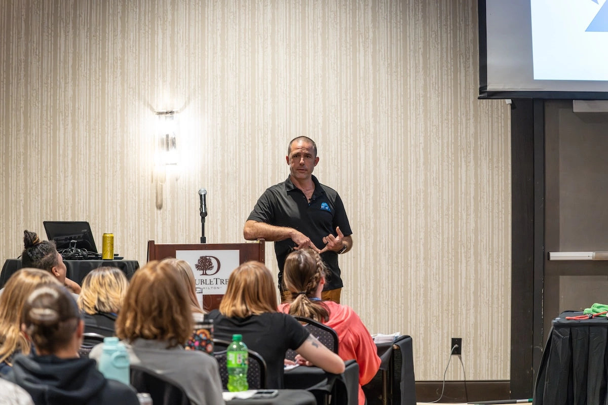 Crafted leather leashes hanging vertically on hooks, displaying black and tan variants with metal hardware and smooth finish.
